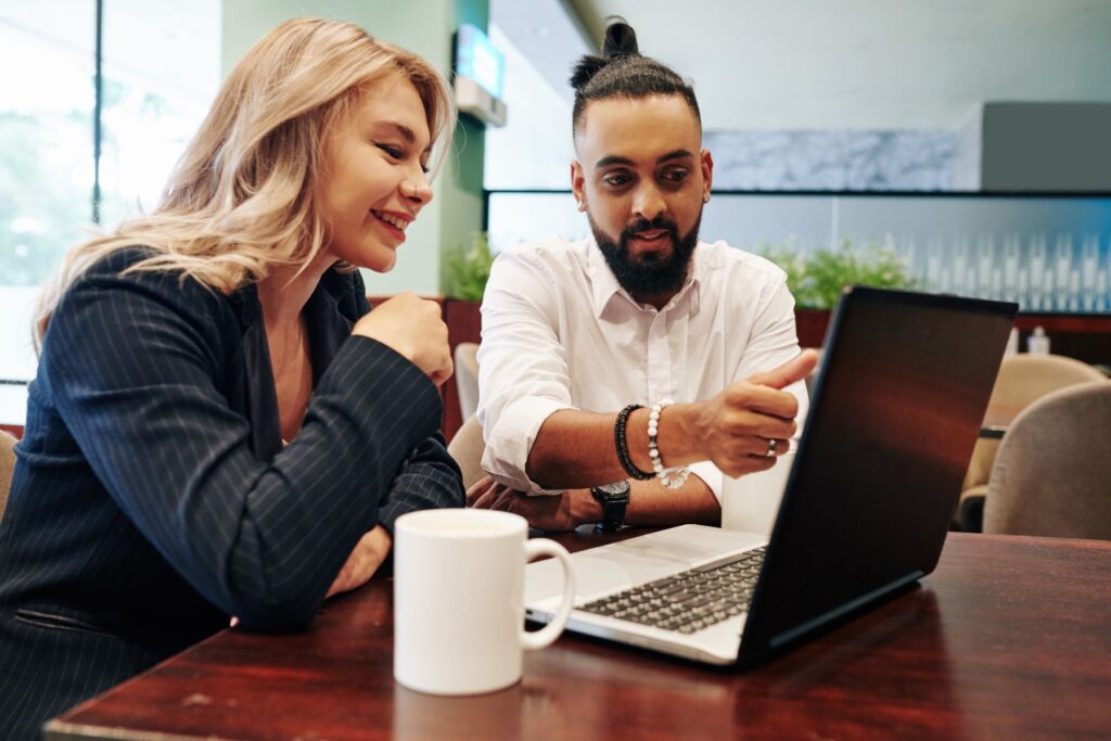 a man and a woman in front of a laptop computer