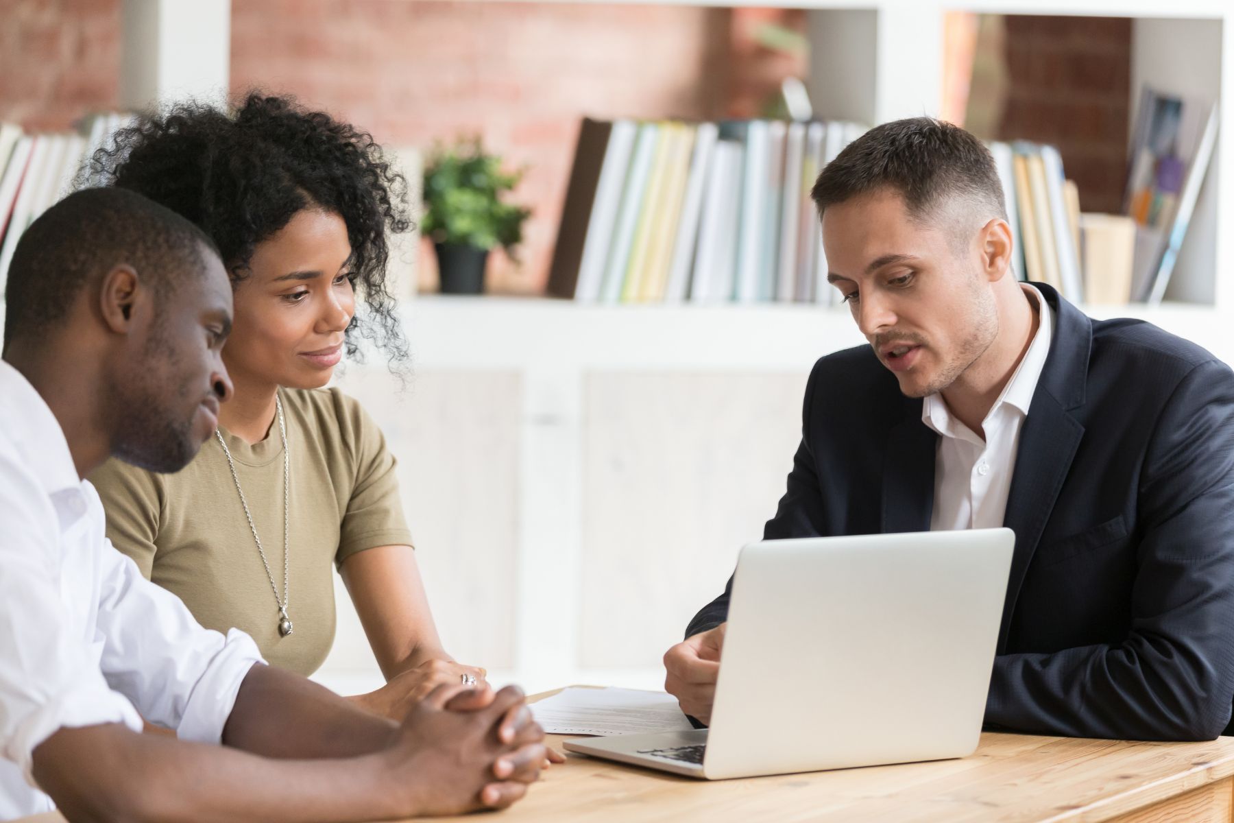 three people having a meeting with a laptop in front of them