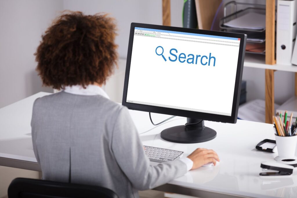 a lady in front of a computer with the word SEARCH on the monitor screen